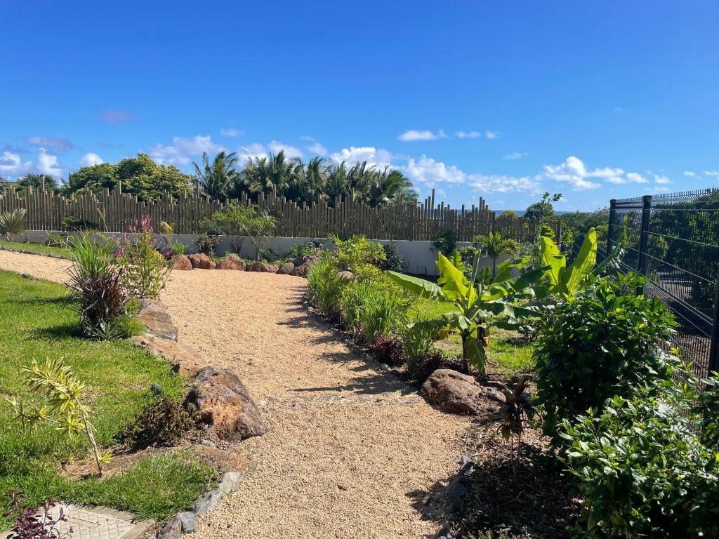 Allée de jardin paysagée sous un ciel bleu dégagé dans une propriété de villa 3 chambres à l'Île Maurice.