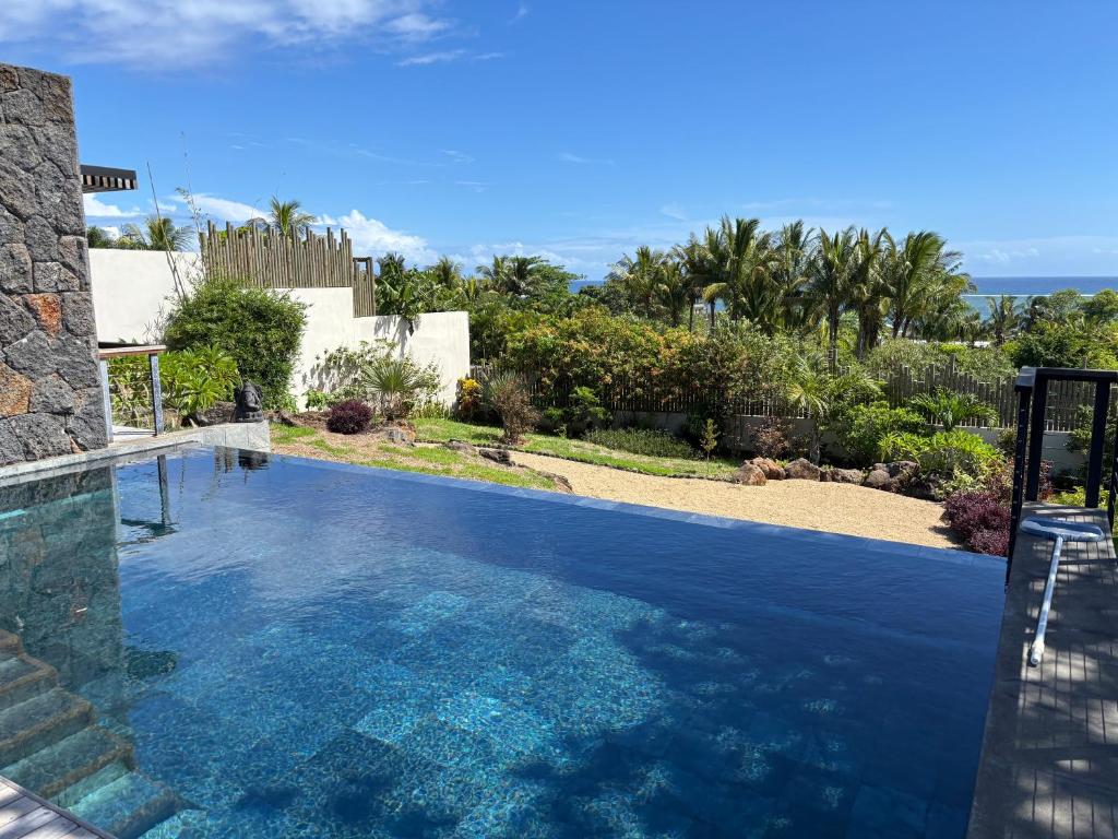 Piscine à débordement avec vue sur l'océan et jardin tropical d'une villa 3 chambres à l'Île Maurice.