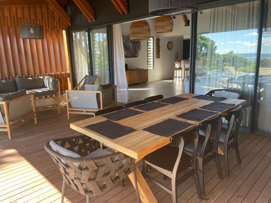 Grande table à manger en bois sur une terrasse couverte avec vue sur le salon extérieur d'une villa 3 chambres à l'Île Maurice.