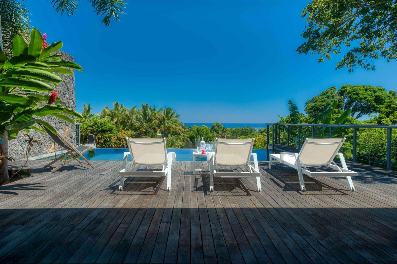 Terrasse en bois aménagée avec chaises longues et piscine privée d'une villa de luxe 3 chambres à l'Île Maurice.
