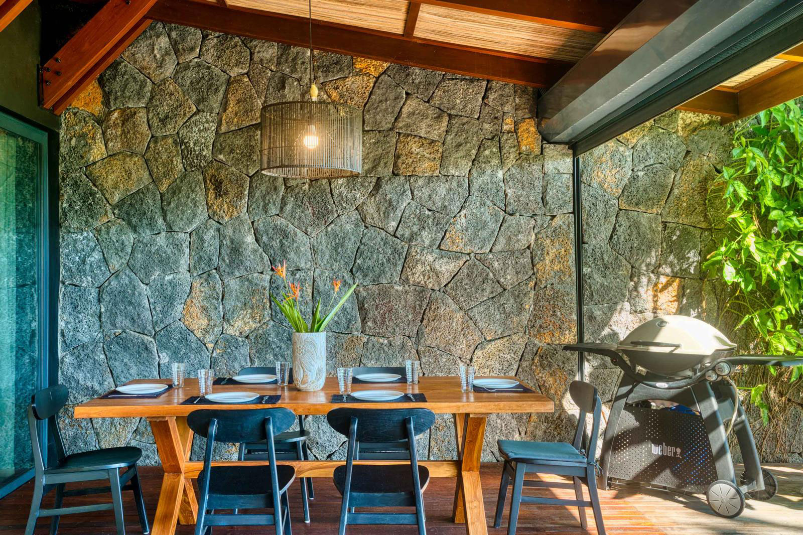 Grande table à manger en bois sur une terrasse couverte avec vue sur le salon extérieur d'une villa 3 chambres à l'Île Maurice.